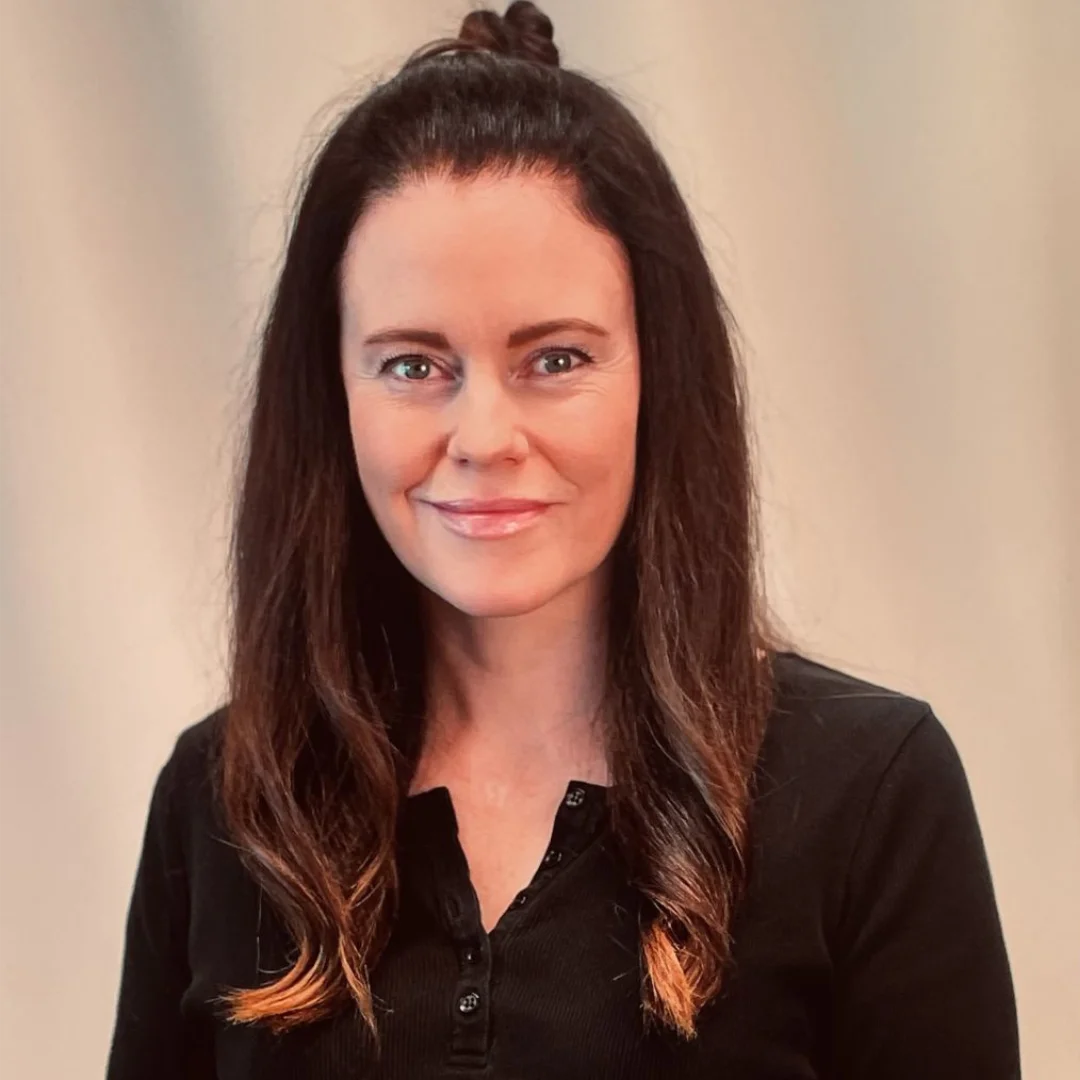 Ceire O’Neill, smiling, in a black top against a pale backdrop.